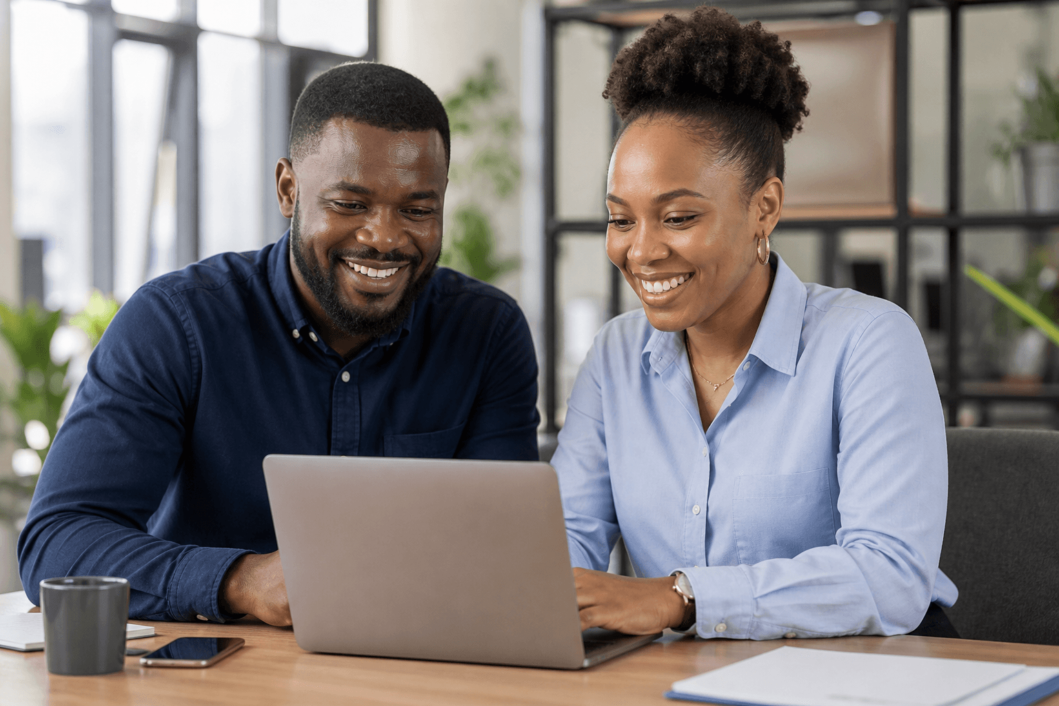 Two professionals collaborating on a laptop in a modern workplace